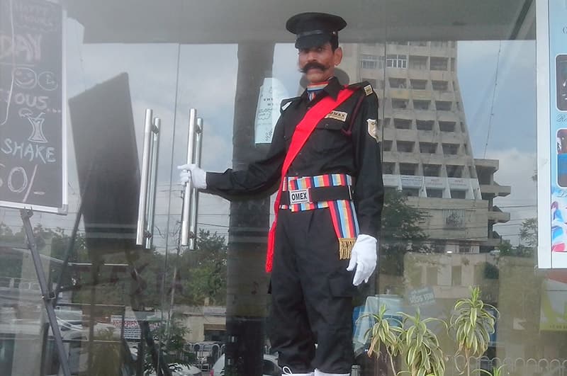 A doorman in ceremonial uniform at a glass entrance